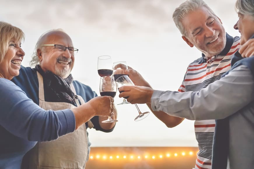 Happy Seniors Friends Drinking Red Wine On Terrace Sunset